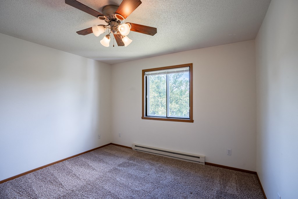 a bedroom with a ceiling fan and a window. Fargo, ND Briar Pointe Apartments
