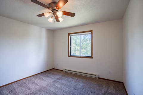 a bedroom with a ceiling fan and a window. Fargo, ND Briar Pointe Apartments