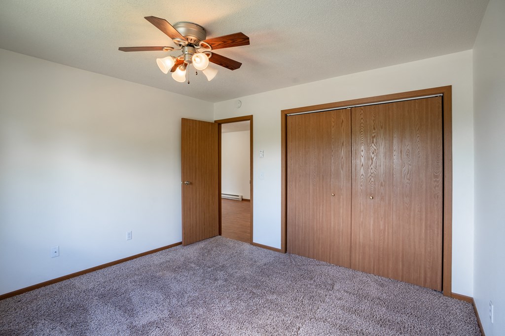 a bedroom with carpet and a ceiling fan. Fargo, ND Briar Pointe Apartments