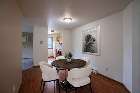 a dining room area with a table and chairs and a living room in the background. Fargo, ND Briar Pointe Apartments