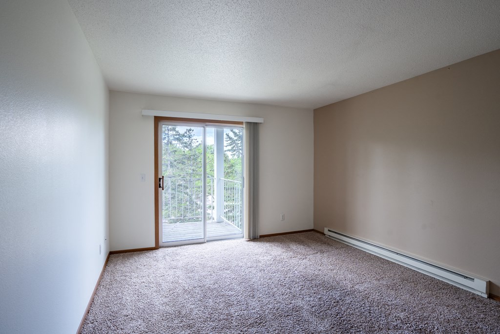 an empty living room with a door to a balcony. Fargo, ND Briar Pointe Apartments