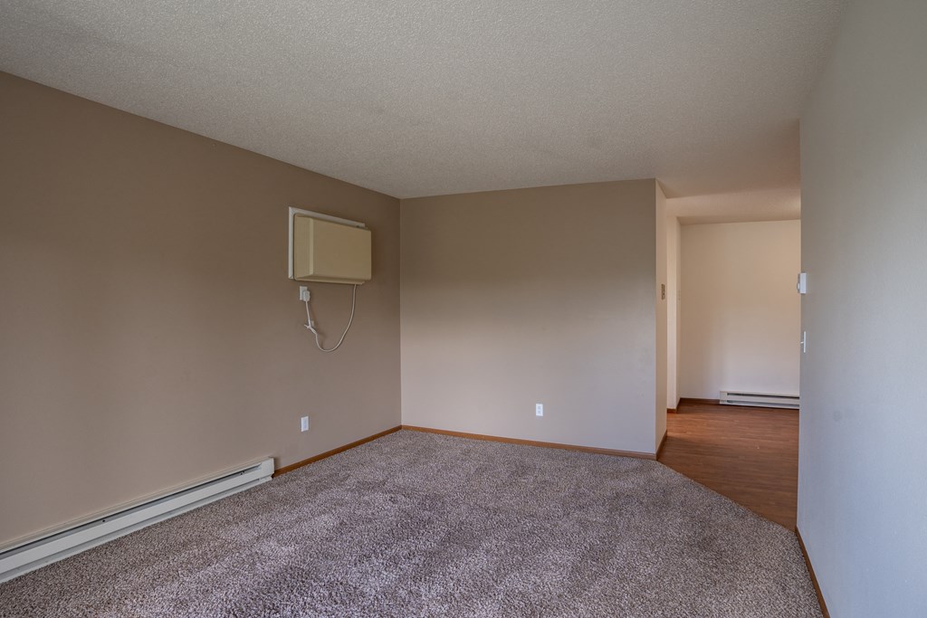 an empty living room with a tv on the wall. Fargo, ND Briar Pointe Apartments