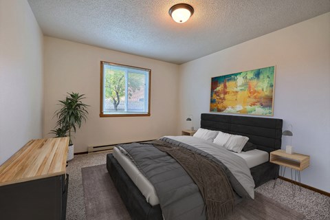 A bedroom with a bed and a dresser. Fargo, ND Brownstone Apartments