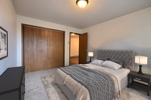Fargo, ND Brownstone Apartments. a bedroom with a bed and a wardrobe