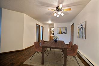 Fargo, ND Brownstone Apartments. a dining room with a wooden table and chairs and a ceiling fan