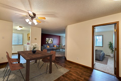 Fargo, ND Brownstone Apartments. a living room and dining room with a wooden table and chairs and a ceiling fan