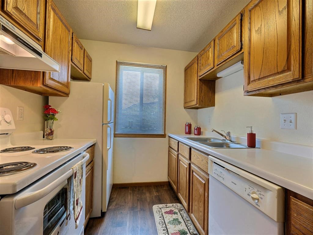 A kitchen with a stove refrigerator and a sink. Fargo, ND Brownstone Apartment.