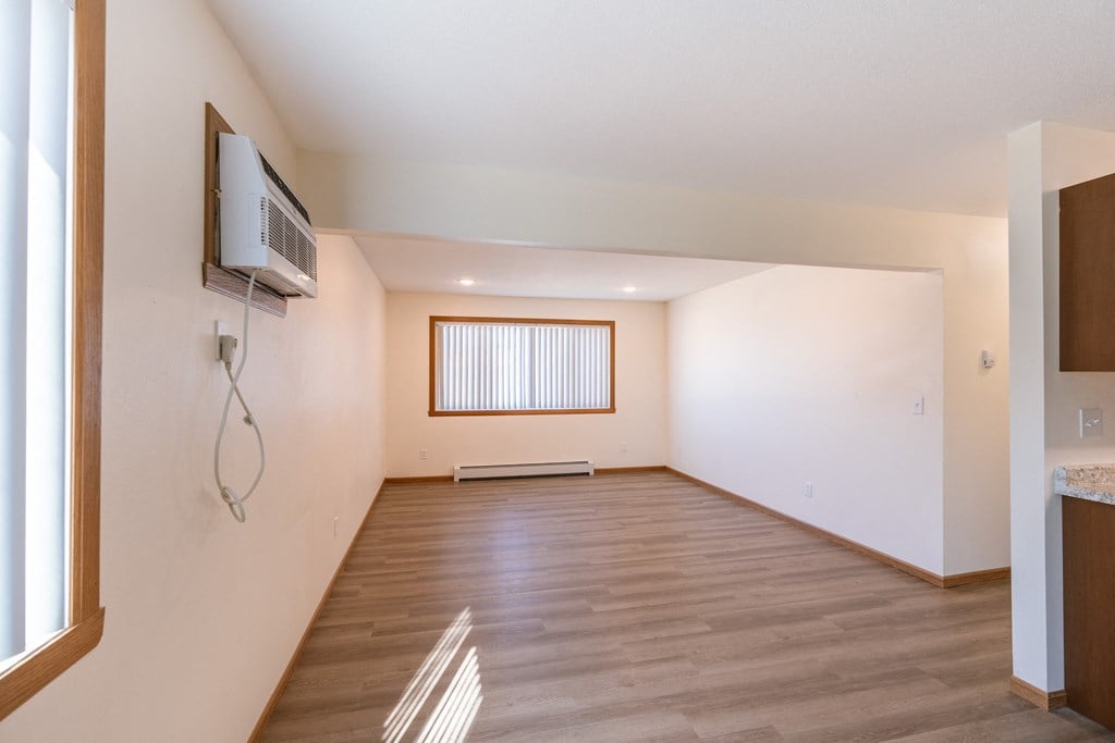 Fargo, ND Cambridge Apartments. A living room with hardwood floors and a tv on the wall