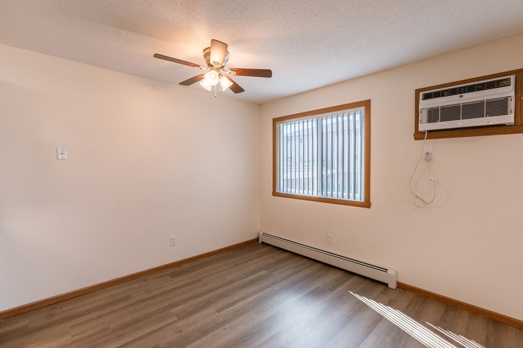 Fargo, ND Cambridge Apartments. A dining room with a ceiling fan, wood floors, and a window.