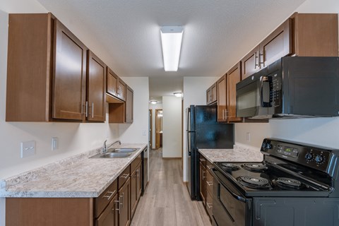 a kitchen with black appliances and marble counter tops and wooden cabinets