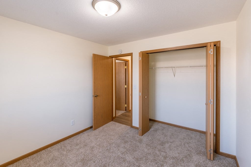 Fargo, ND Cambridge Apartments. A bedroom with a closet and a closet door open
