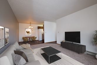 Fargo, ND Carlton Place Apartments. a living room with a white couch and a black coffee table in front of a flat screen