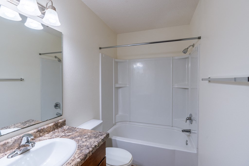 a bathroom with a tub and a sink and a mirror. Fargo, ND Carlton Place Apartments