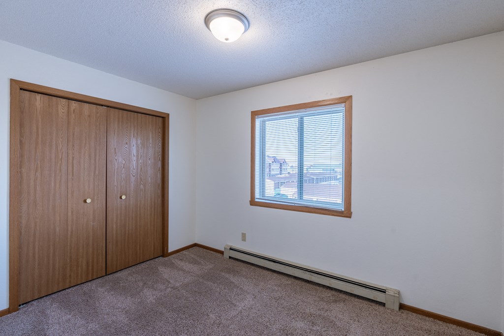 an empty living room with a window and a closet. Fargo, ND Carlton Place Apartments