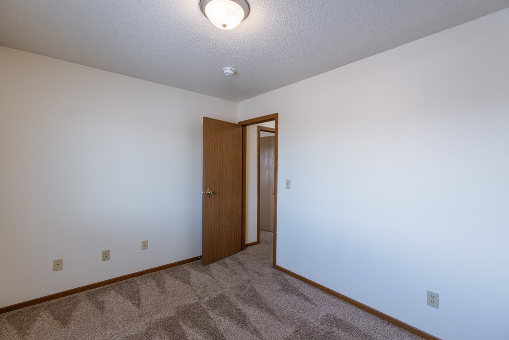 a bedroom with carpeted flooring and a door to a closet. Fargo, ND Carlton Place Apartments