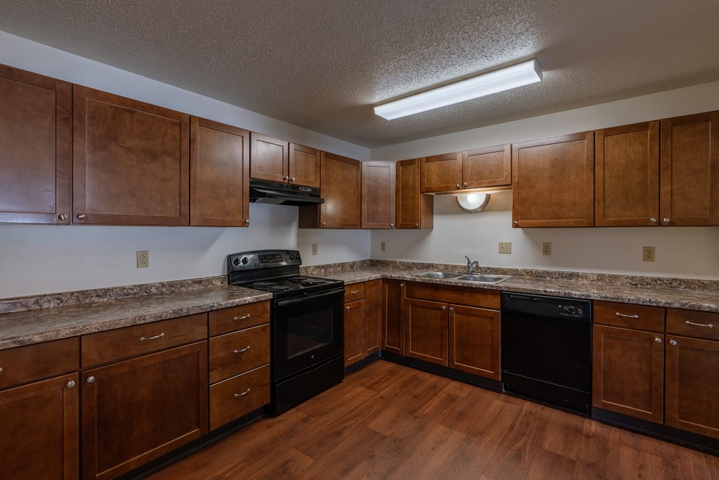 a kitchen with wooden cabinets and black appliances. Fargo, ND Carlton Place Apartments