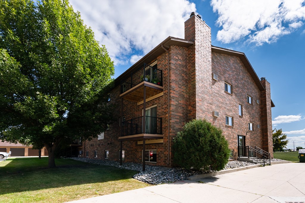 Fargo, ND Cedars 2 Apartments. a red brick building with a stone chimney and a tree in front of it
