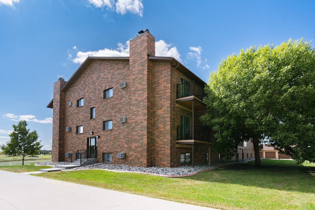 Fargo, ND Cedars 4 Apartments. A red brick building with a tree in front of it