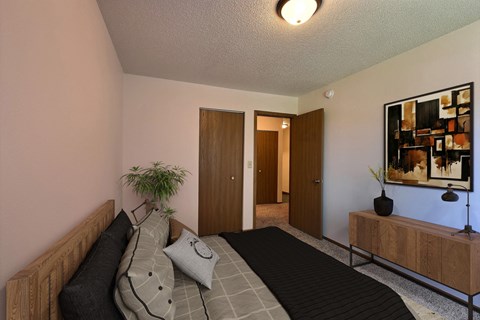 a bedroom with a bed and a potted plant. Fargo, ND Chestnut Ridge Apartments