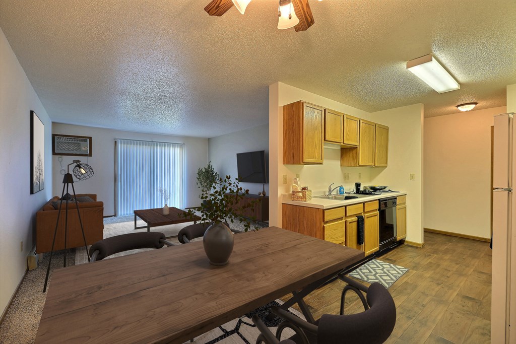 an open living room with a dining room table and a kitchen. Fargo, ND Chestnut Ridge Apartments