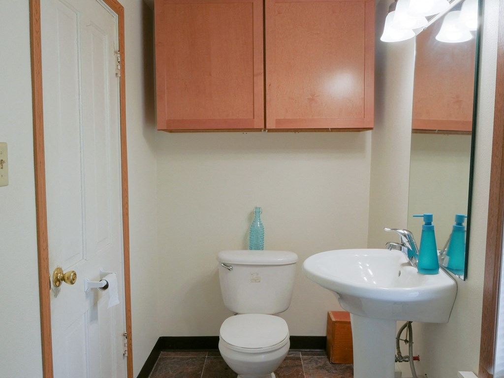 Fargo, ND Cityside Apartments. A bathroom with a pedestal sink and a cabinet above the toilet