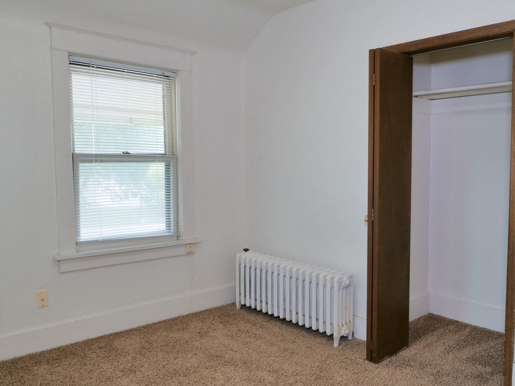Fargo, ND Cityside Apartments  a bedroom with a radiator, window, and a small closet