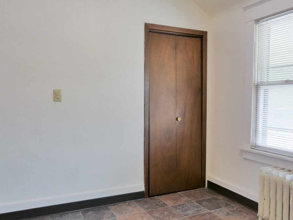 Fargo, ND Cityside Apartments  a wooden door to a pantry in a white-walled room with a window and radiator