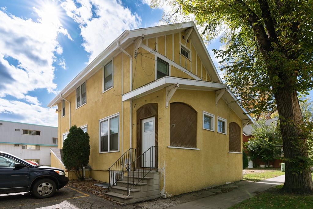 a yellow house with a car parked in front of it. Fargo, ND Cityside Apartments
