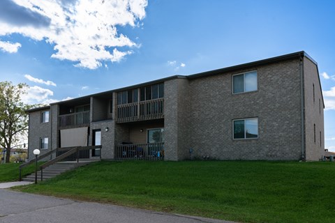 an exterior view of a brick apartment building with green grass