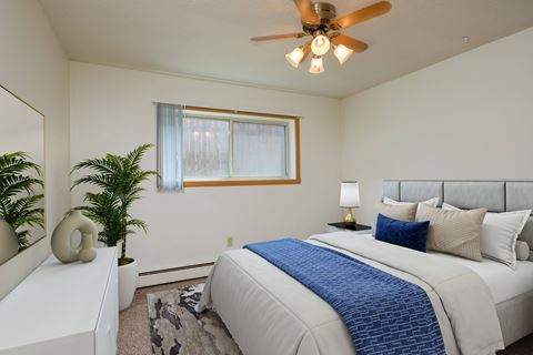 a bedroom with a large bed and a ceiling fan. Fargo, ND Country Club Apartments.