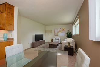 a living room with a glass table and a couch and a tv. Fargo, ND Country Club Apartments.