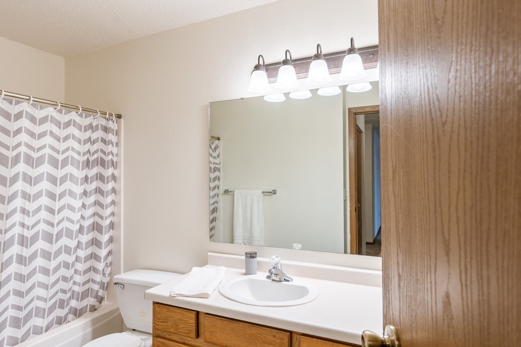a bathroom with a sink and a mirror and a shower. Fargo, ND Country Edge Apartments