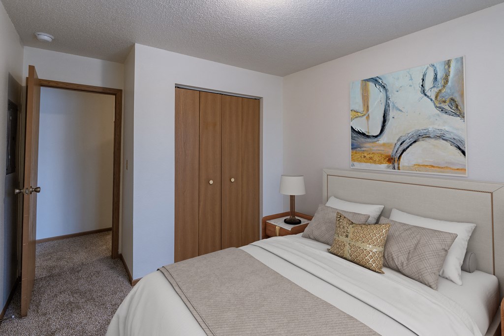 a bedroom with a bed and a door to a closet. Fargo, ND Country Edge Apartments