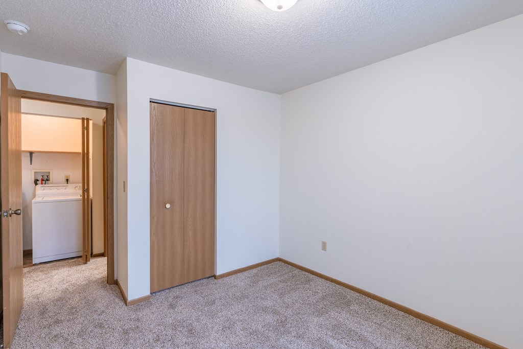 a bedroom with a door to a hallway. Fargo, ND Country Edge Apartments