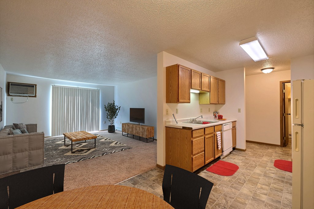an open kitchen and living room with a dining room table. Fargo, ND Country Edge Apartments
