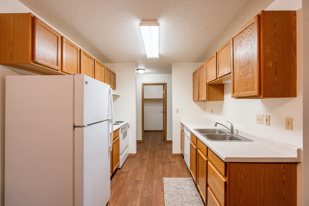a kitchen with white appliances and wood cabinets. Fargo, ND Country Edge Apartments