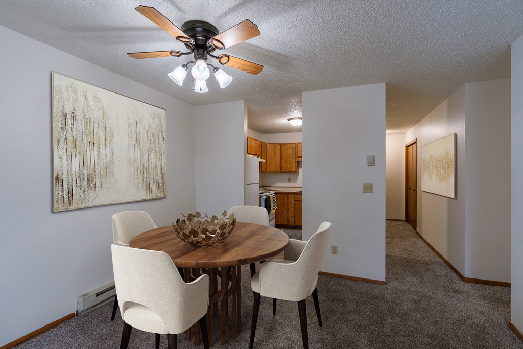 a dining room with a table and chairs and a ceiling fan. Fargo, ND Crescent Park Apartments