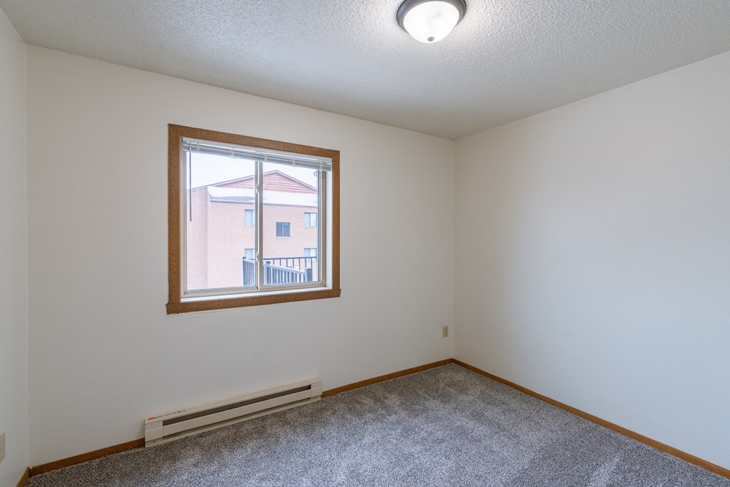 the living room of an empty house with a large window.Fargo, ND Crescent Park Apartments