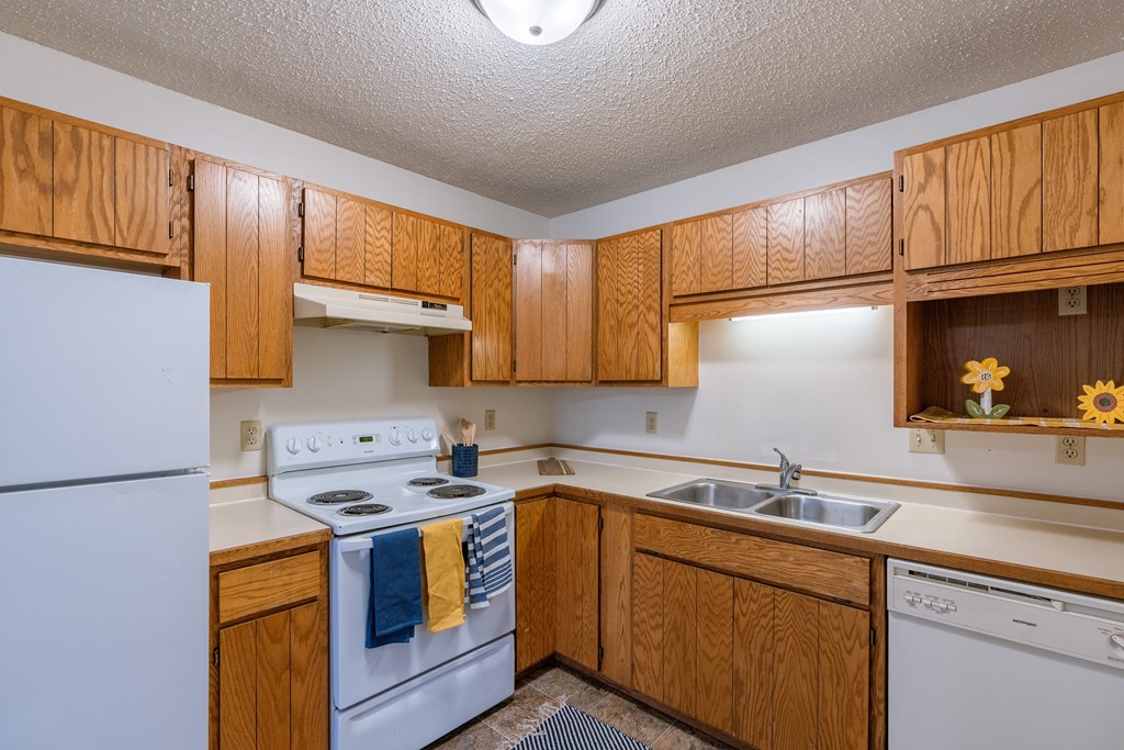 a kitchen with white appliances and wooden cabinets. Fargo, ND Crescent Park Apartments