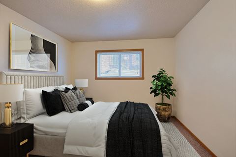 Fargo, ND Dakota Manor Apartments. a bedroom with a large bed and a plant in the corner of the room