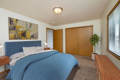 Fargo, ND Danbury Apartments. a bedroom with white walls and a blue bedspread