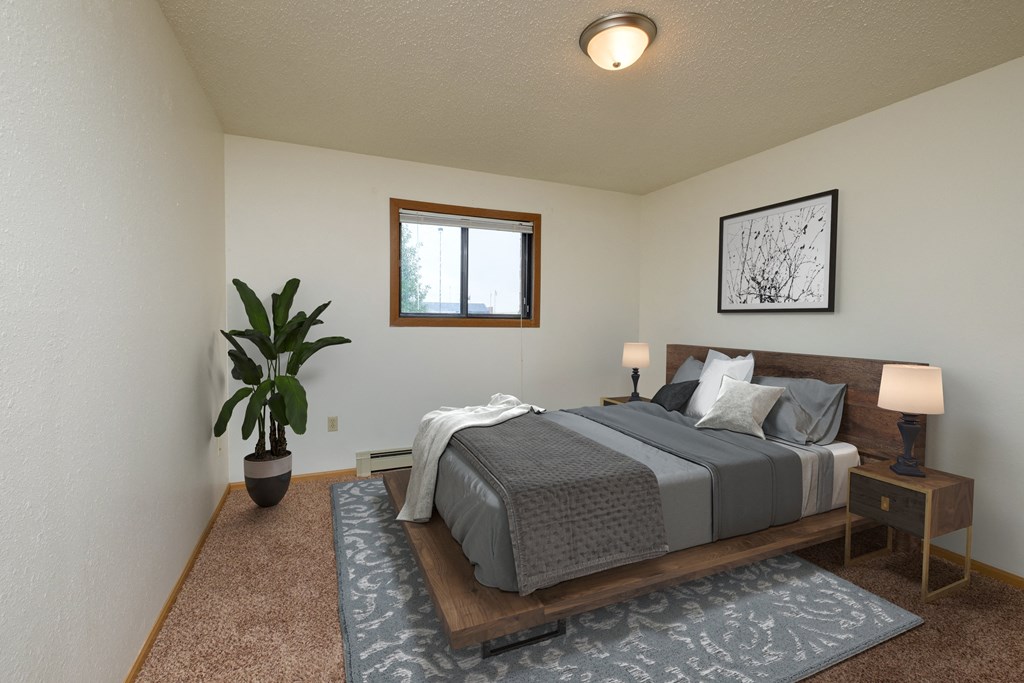 Fargo, ND Dynasty Apartments a bedroom with a large bed and a potted plant