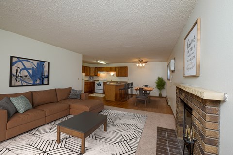 Fargo, ND Dynasty Apartments. a living room with a fireplace and a kitchen in the background