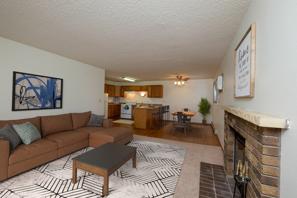 Fargo, ND Dynasty Apartments. a living room with a fireplace and a kitchen in the background