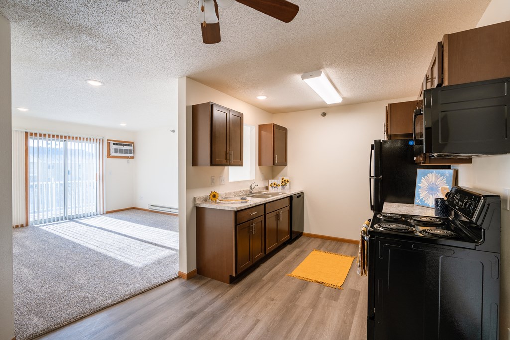 the view of a kitchen and living room with a sliding glass door. Fargo, ND Eagle Run Apartments