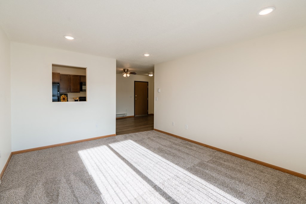 a living room with white walls and a carpeted floor. Fargo, ND Eagle Run Apartments