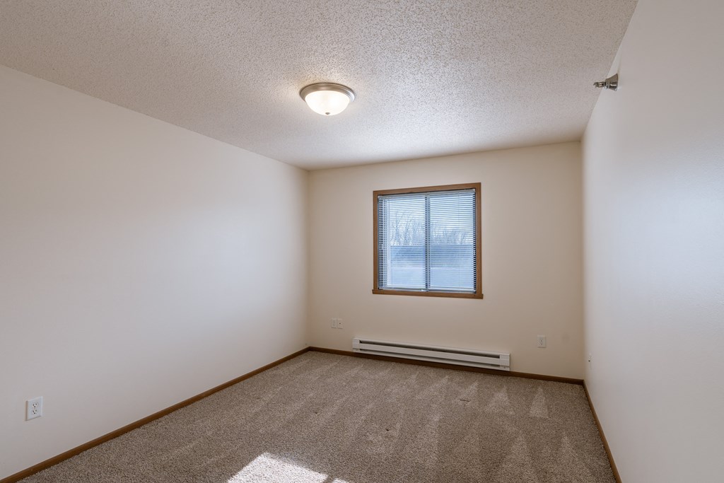 a bedroom with carpet and a window. Fargo, ND Eagle Run Apartments