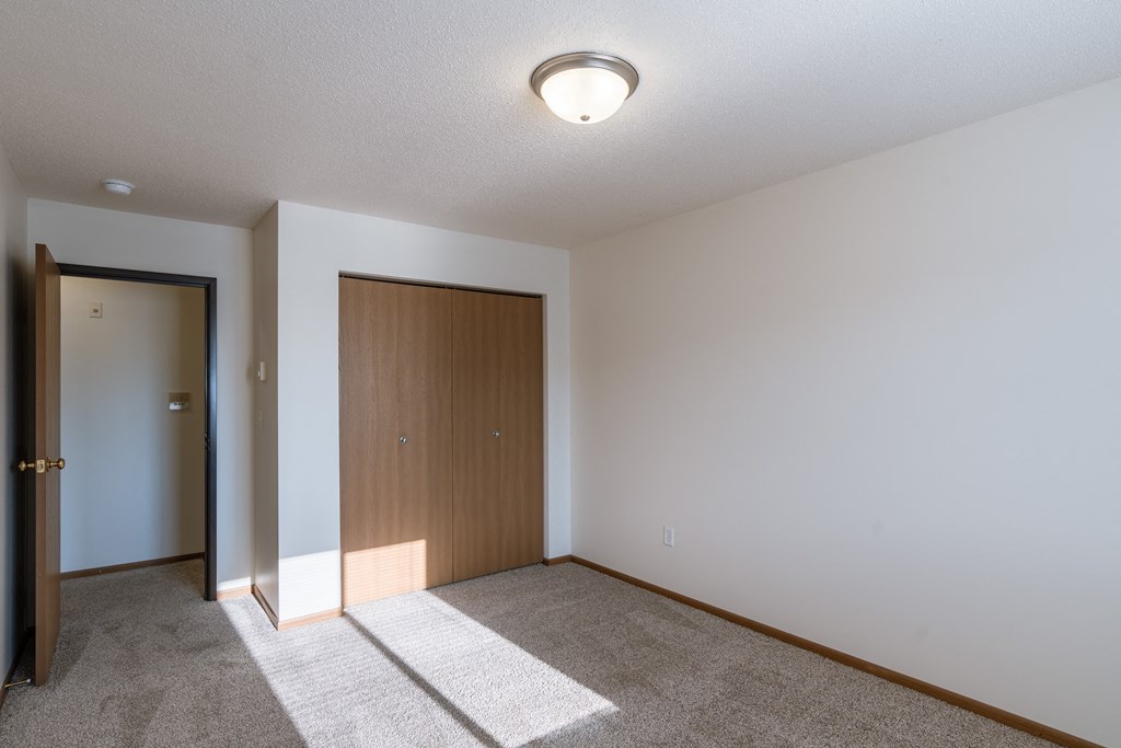 a bedroom with white walls and a door to a closet. Fargo, ND Eagle Run Apartments