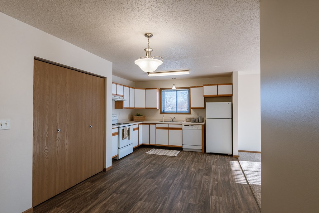 an empty kitchen with white appliances and a wooden floor. Fargo, ND Eagle Run Apartments