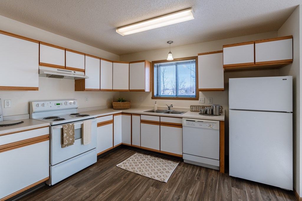 an empty kitchen with white appliances and wooden cabinets. Fargo, ND Eagle Run Apartments